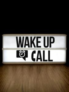 Bright lightbox displaying 'Wake Up Call' on a wooden surface with a black background.
