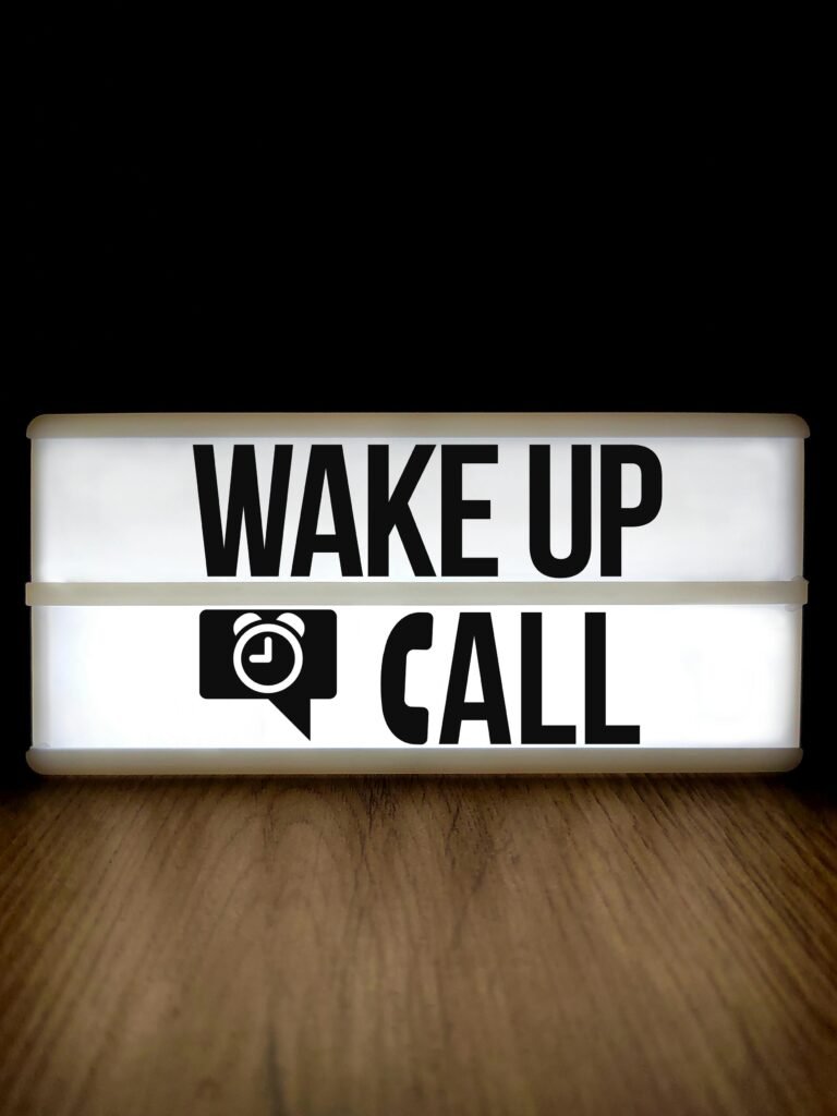 Bright lightbox displaying 'Wake Up Call' on a wooden surface with a black background.