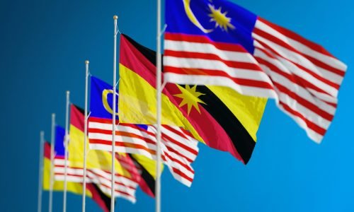 Vibrant display of Malaysian and Sarawak flags symbolizing unity and patriotism against a clear blue sky.